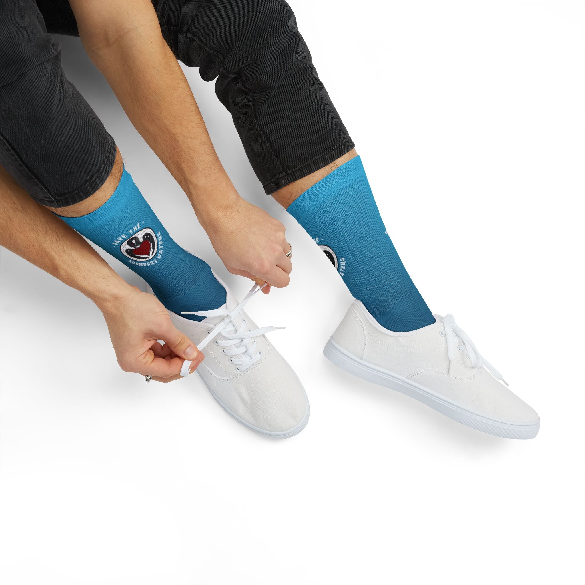 Lifestyle photo of blue crew socks with loon illustration on model cropped to show tying shoe