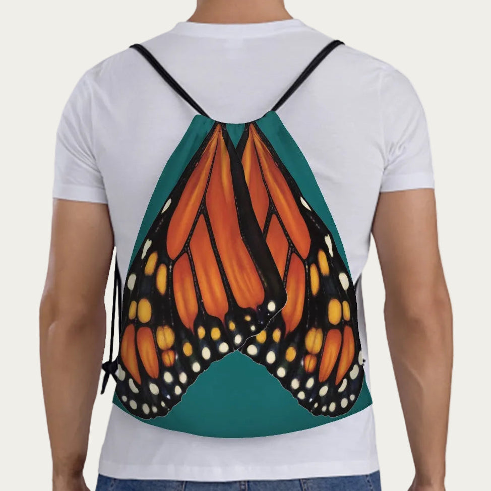 Model wearing jade‑green drawstring backpack showing full‑scale monarch butterfly wings printed across the back panel.