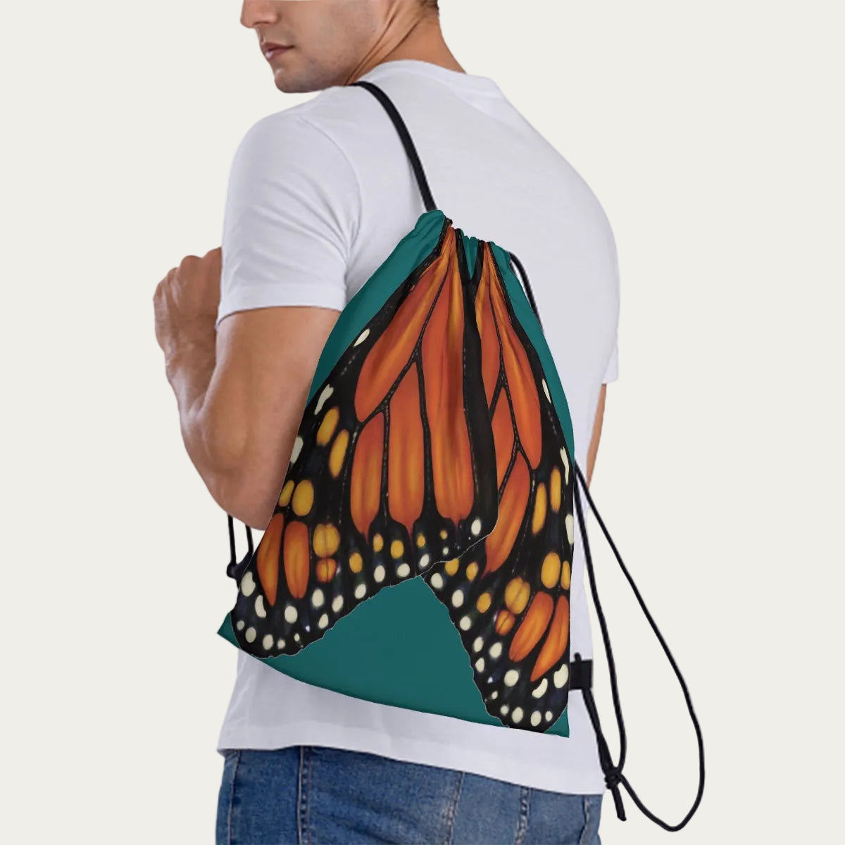 Model wearing jade‑green drawstring backpack slung over one shoulder, showing side view of the monarch wing artwork.
