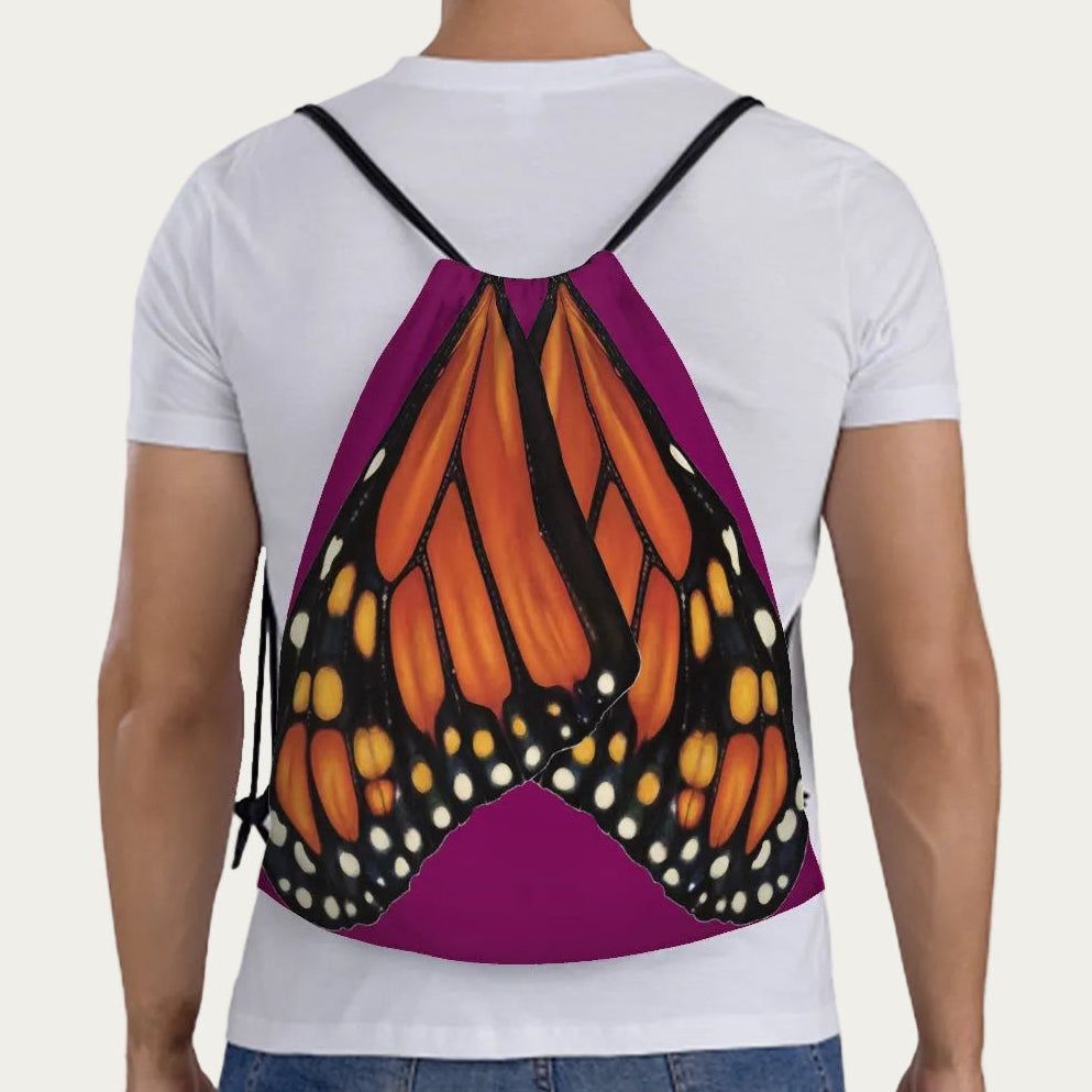 Model wearing plum drawstring backpack showing full‑scale monarch butterfly wings printed across the back panel.