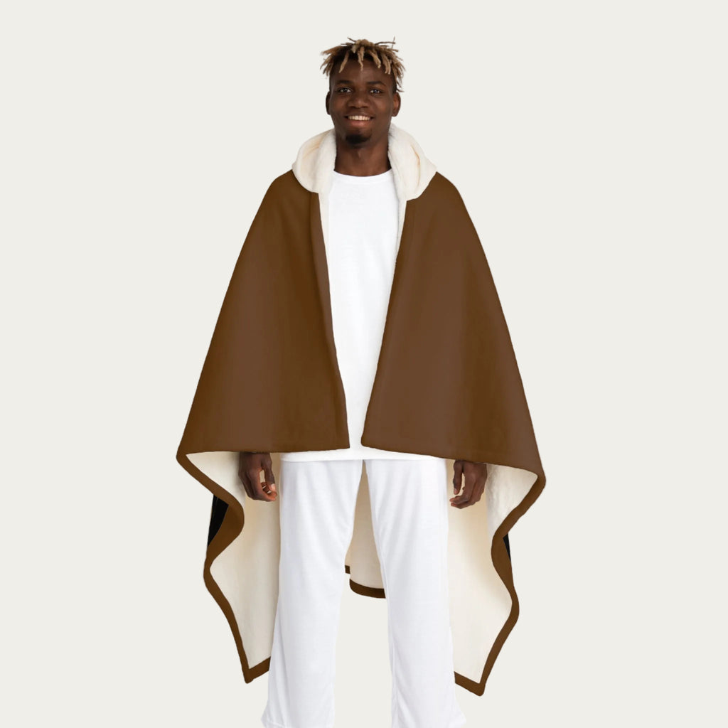 Front view of model wearing brown hooded sherpa blanket hanging straight down like a cape, showing cream sherpa‑lined hood and smooth front panel.