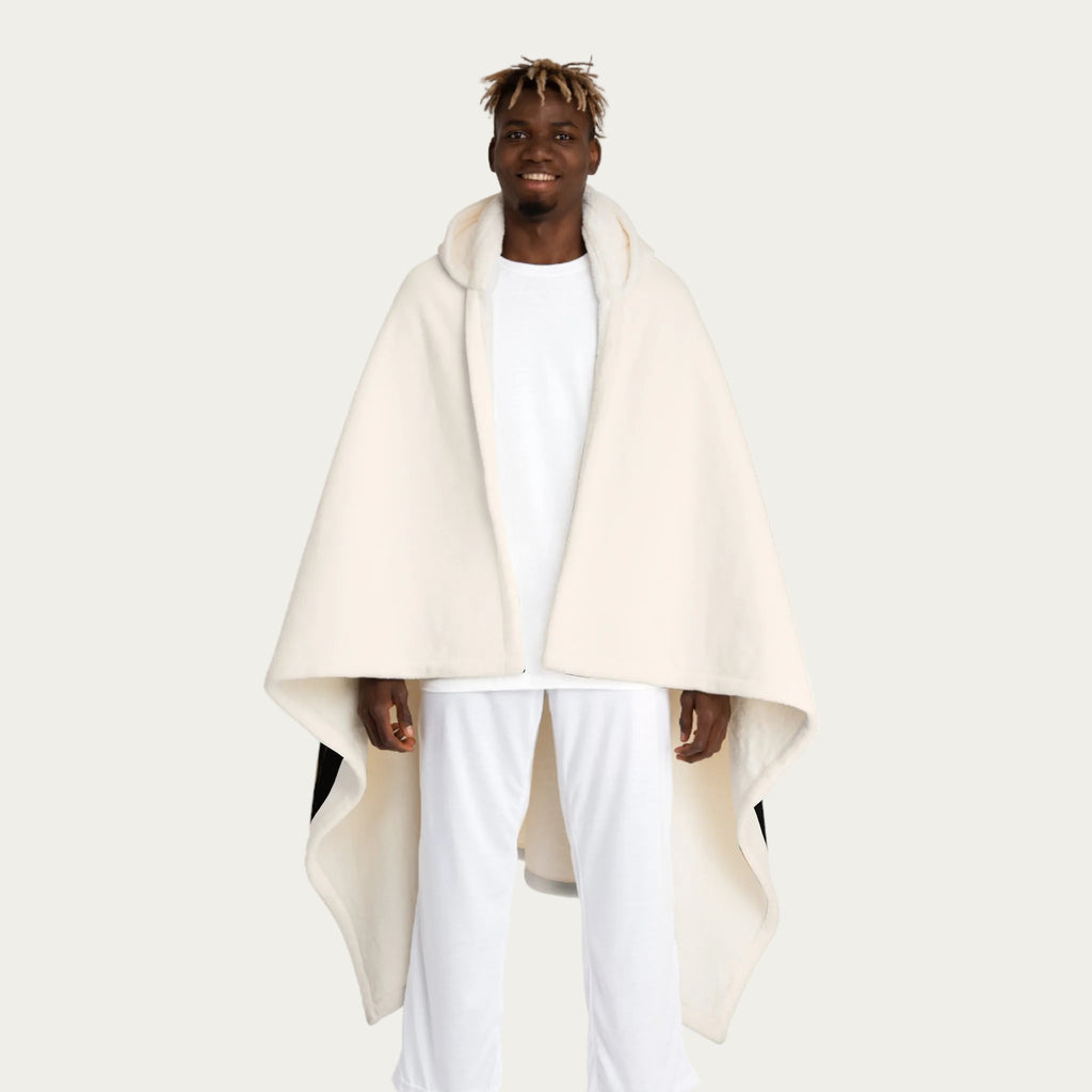 Front view of model wearing cream hooded sherpa blanket hanging straight down like a cape, showing smooth front panel and cream sherpa‑lined hood.