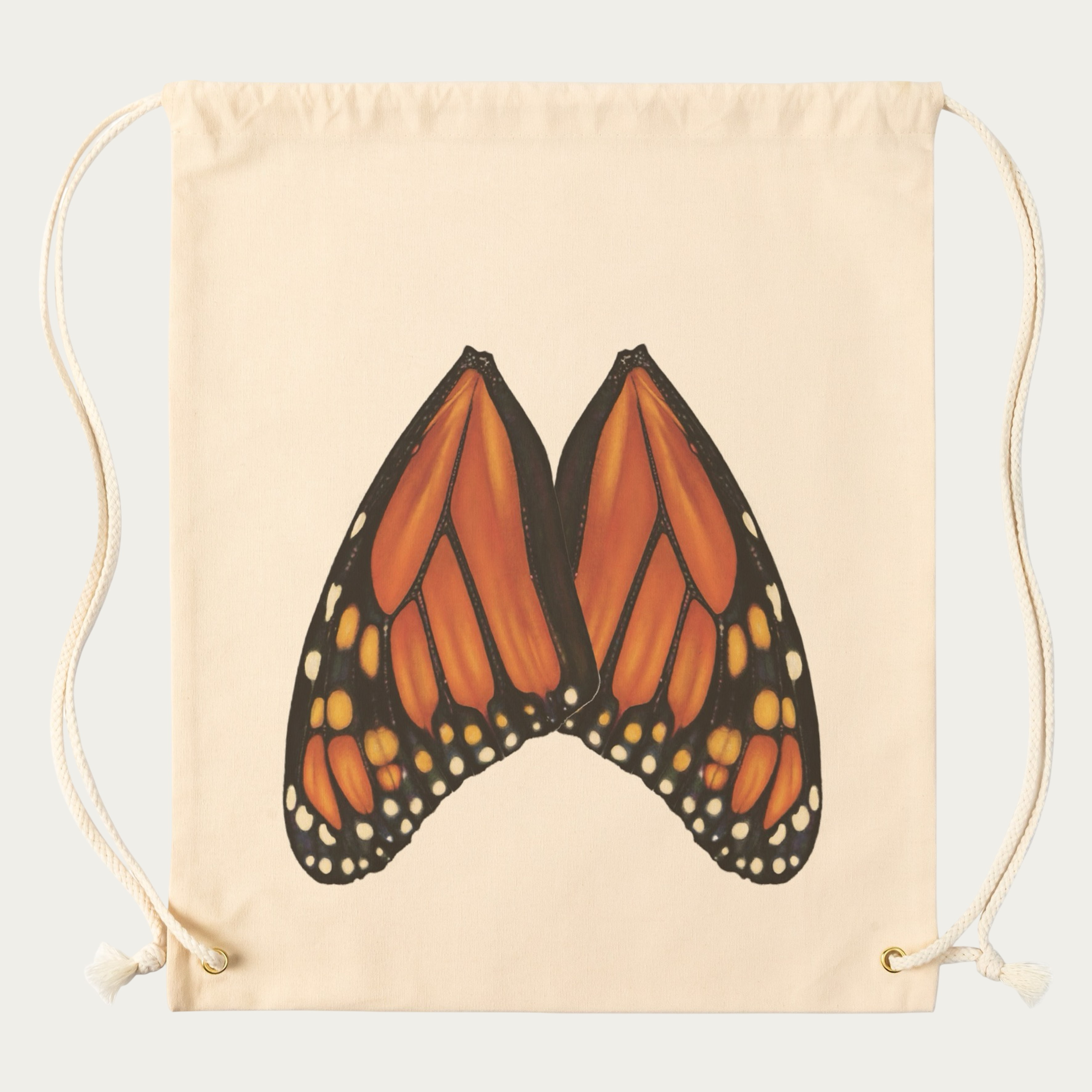 Flat lay natural‑canvas backpack showing full back panel monarch butterfly wings and quick sports bag drawstring