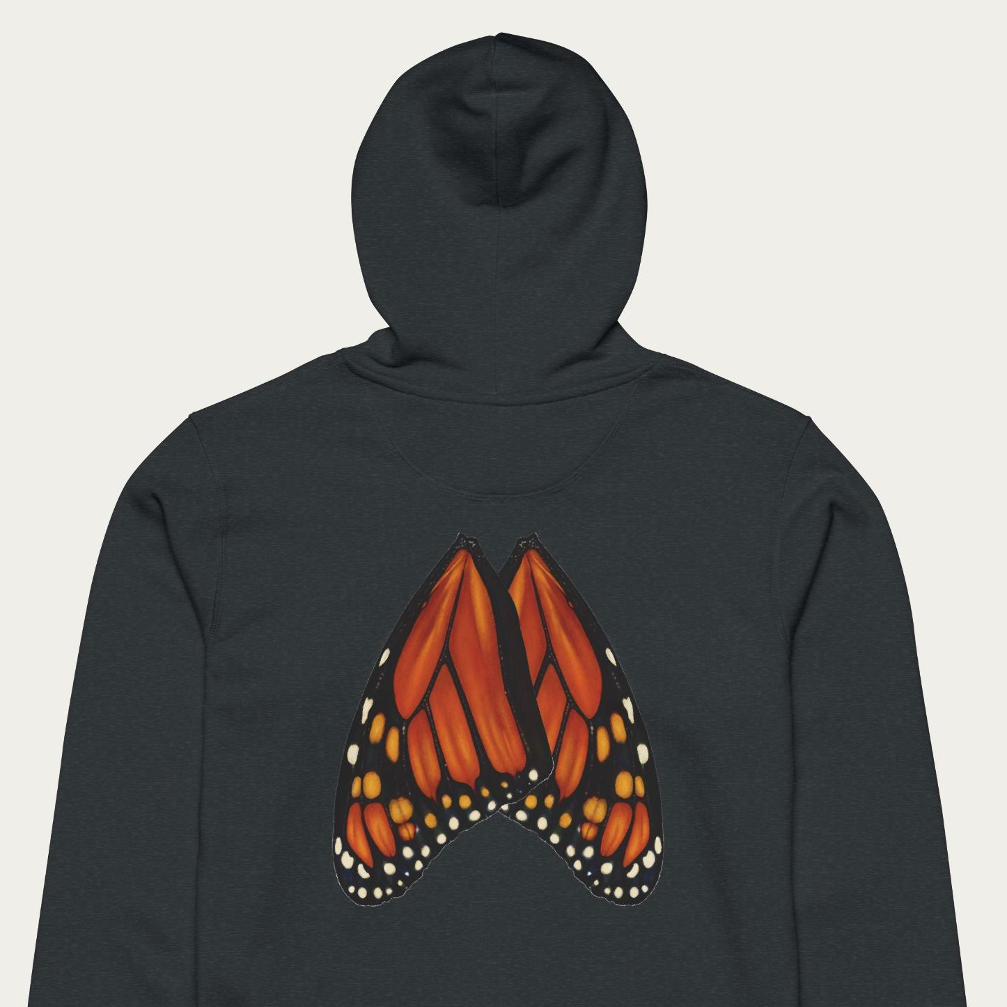 Close-up flat lay of dark heather grey hoodie featuring detailed monarch butterfly wing artwork across the back panel.