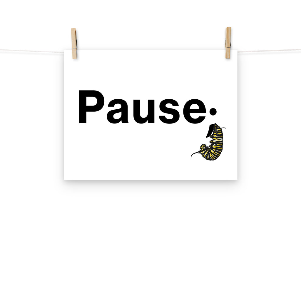 12×16 art print hanging from a clothesline with wooden pins, showing the “Pause.” design and monarch caterpillar illustration on matte paper.