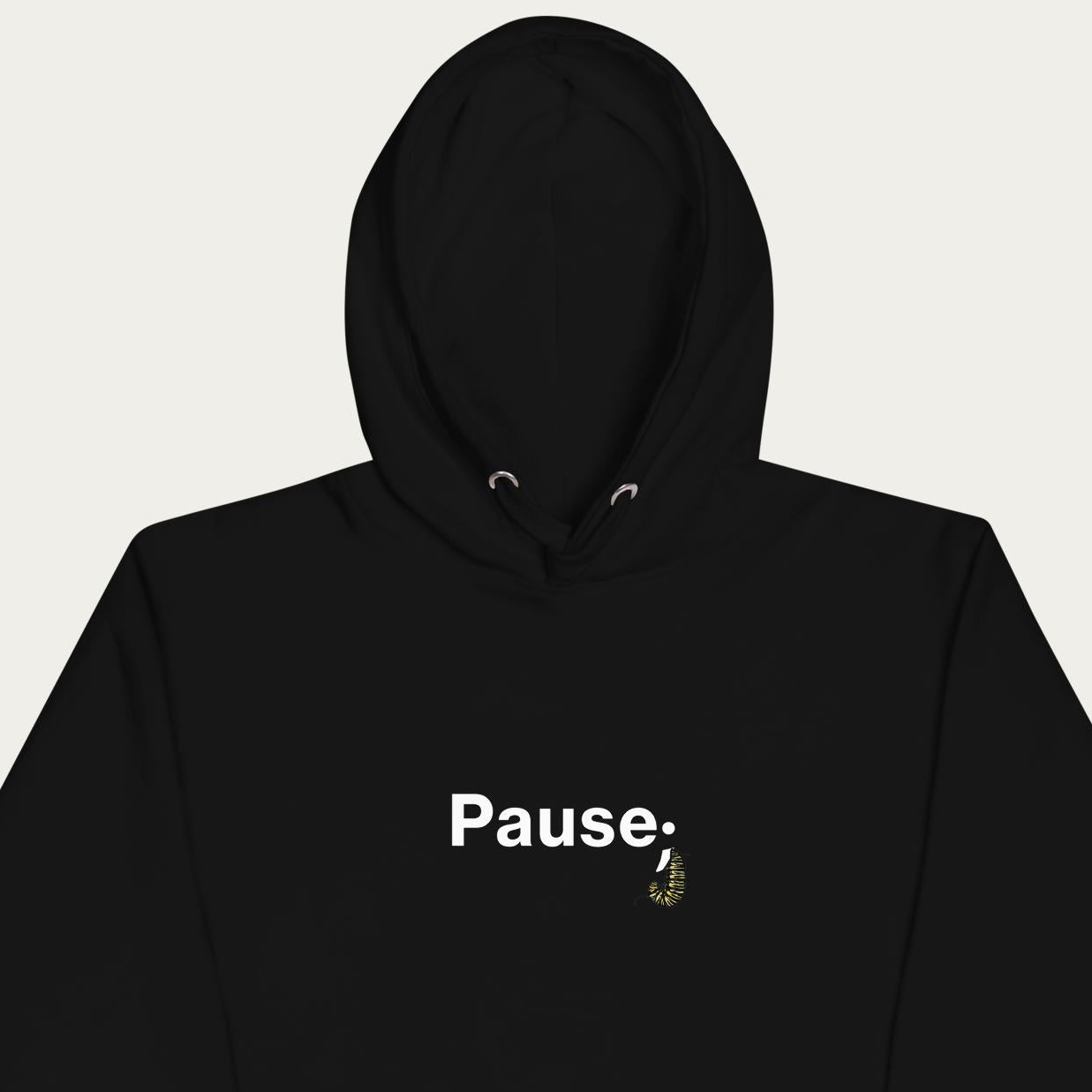 Close‑up crop of black hoodie showing detailed monarch caterpillar illustration forming the semicolon in the “Pause;” design.