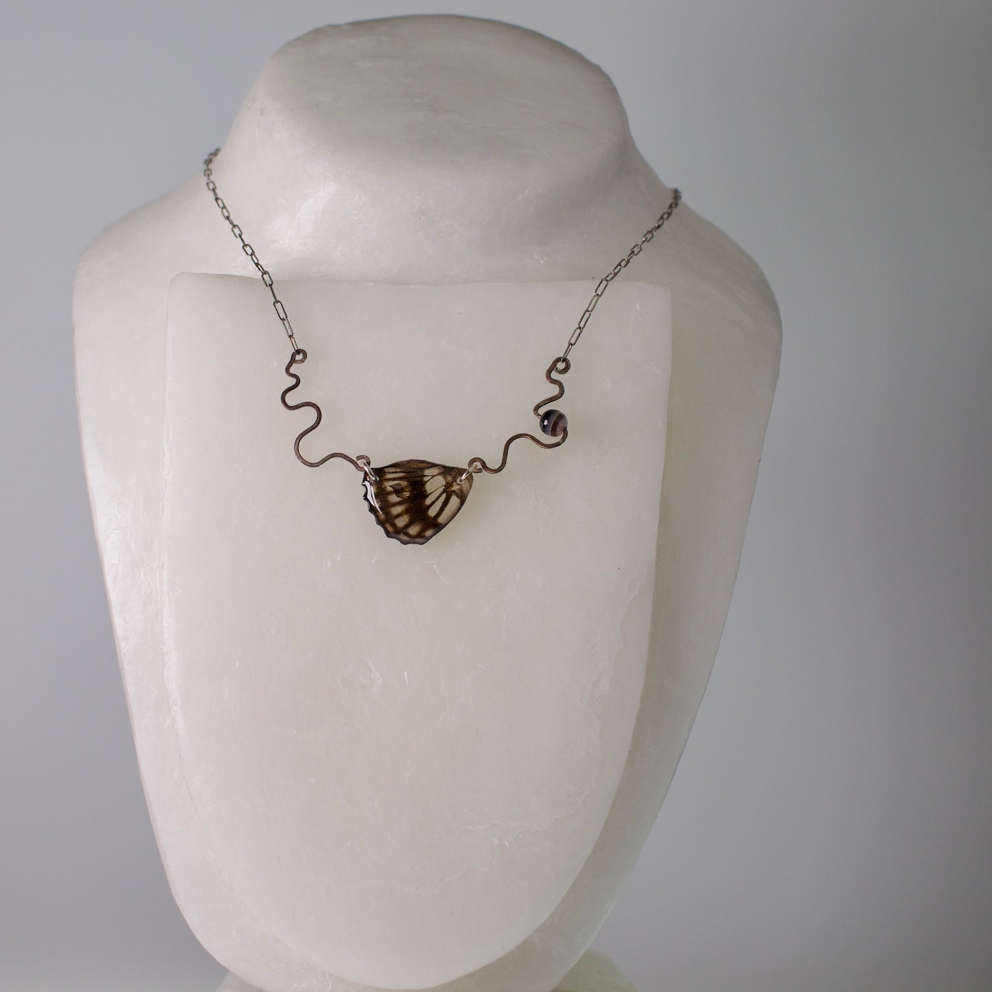 real butterfly wing necklace black and white common sailor butterflies hand forged sterling silver banded agate on stand