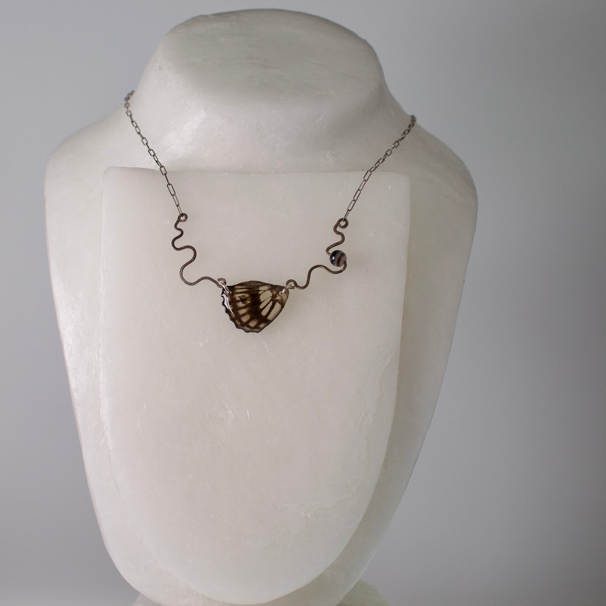 real butterfly wing necklace black and white common sailor butterflies hand forged sterling silver banded agate on stand