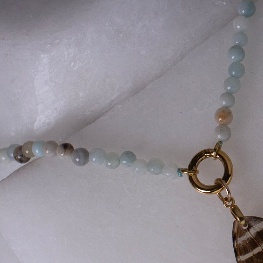 real butterfly wing necklace blue stone beaded gold front clasp close up on wax